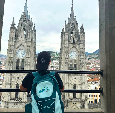 Ein junger Mann mit einem schwarzen Hut blickt auf die beeindruckenden Türme einer Kathedrale in der Stadt.
