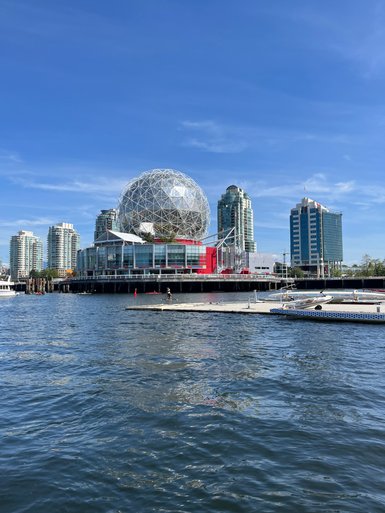 Die beeindruckende Geodätische Kuppel in Vancouver spiegelt sich im ruhigen Wasser, umgeben von modernen Wolkenkratzern.