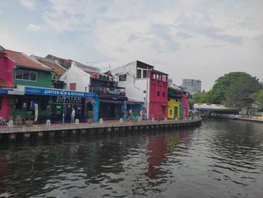 Vom Ufer aus fällt der Blick auf den Fluss und bunte Häuserfassaden in Malakka – Malaysia & Borneo mit Kindern