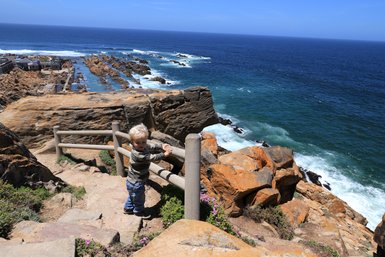 Baby schaut von oben auf das Meer in Mossel Bay entlang der Garden Route – Garden Route Familienreise