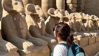 Besucherin steht vor der beeindruckenden Reihe von Widder-Sphinxen im Karnak-Tempel – Ägypten Reise mit Kindern