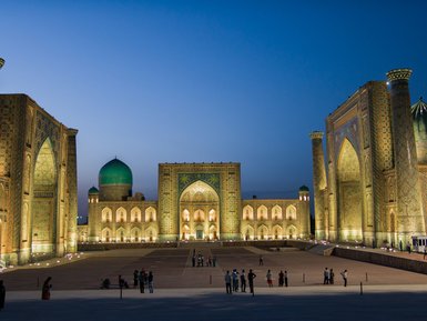Die beeindruckende Architektur der Registan in Samarkand erstrahlt in warmem Licht, während Menschen die Szenerie genießen.