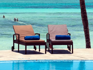 Zwei Liegen mit blauen Handtüchern stehen am Pool, umgeben von einem atemberaubenden Blick auf das türkisfarbene Wasser.