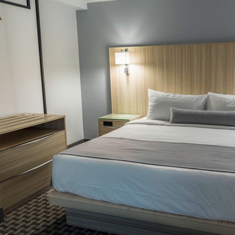 Ein modernes Hotelzimmer mit einem großen Bett, eleganten Holzmöbeln und sanften Farben, das eine entspannende Atmosphäre schafft.