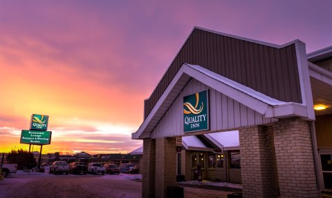 Die Fassade des Quality Inn in Edmonton wird von einem beeindruckenden Sonnenuntergang in lila und orange beleuchtet.