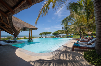 Ein einladender Poolbereich mit Palmen und Liegen, ideal für Entspannung unter dem strahlend blauen Himmel.