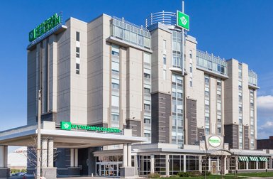 Das Wyndham Garden Hotel zeigt eine moderne Architektur mit großen Fenstern und einem klaren blauen Himmel im Hintergrund.