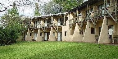 Eine Lodge mit mehreren Zimmern, umgeben von üppigem Grün und Bäumen, bietet eine einladende Atmosphäre für Gäste.