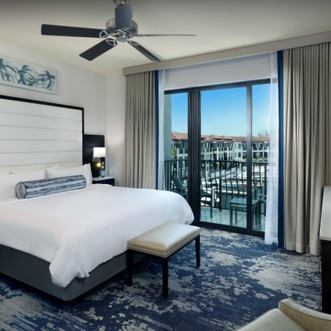 Ein modernes Hotelzimmer mit einem großen Bett, einem Balkon und Blick auf den Hafen von Naples, Florida.