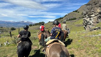 Eine Gruppe von Reitern auf Pferden erkundet die malerische Landschaft Patagoniens unter einem strahlend blauen Himmel.