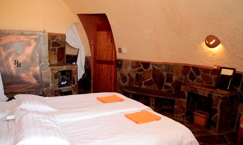 Ein gemütliches Zimmer mit zwei Einzelbetten, weißen Bettlaken und orangefarbenen Handtüchern auf der Bettdecke.