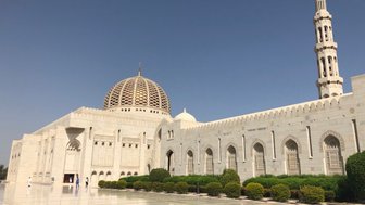 Die beeindruckende Moschee mit einer großen Kuppel und einem hohen Minarett steht vor einem klaren blauen Himmel.
