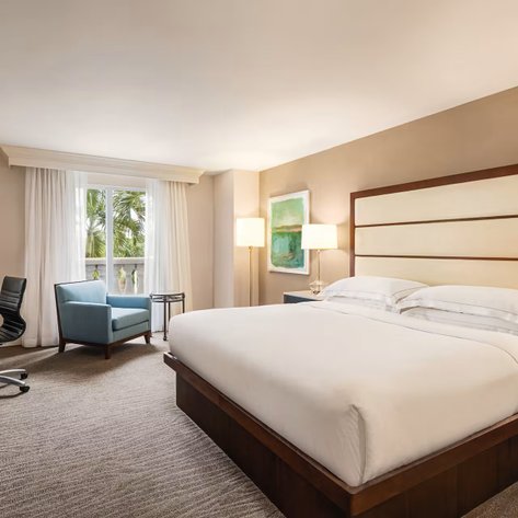 Ein stilvolles Hotelzimmer mit einem großen Bett, einer sonnendurchfluteten Ecke und einem gemütlichen Sessel für Entspannung.