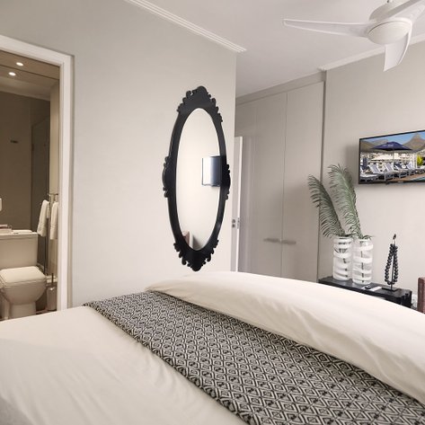 Ein modernes Hotelzimmer mit einem großen Bett, einem eleganten Spiegel und einem Fernseher an der Wand.