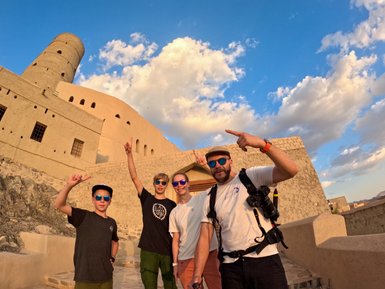 Familie macht Selfie mit Gebäude vom Bahla Fort im Oman – Oman Reise mit Kindern
