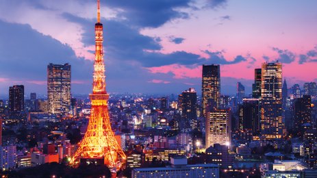 Der Tokyo Tower leuchtet in warmen Farben, während die Stadt unter einem dramatischen Abendhimmel erstrahlt.
