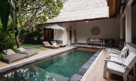 Ein eleganter Innenhof mit einem glitzernden Pool, umgeben von üppigem Grün und gemütlichen Liegen zum Entspannen.