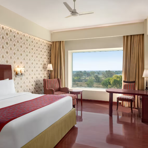 Ein elegantes Hotelzimmer mit einem großen Fenster, das einen Blick auf die grüne Landschaft bietet.