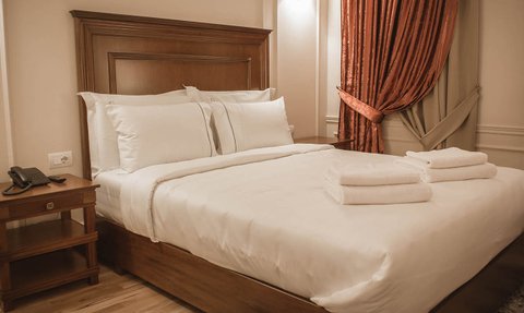 Ein elegantes Hotelzimmer mit einem großen Bett, weißen Kissen und frischen Handtüchern auf der Bettdecke.