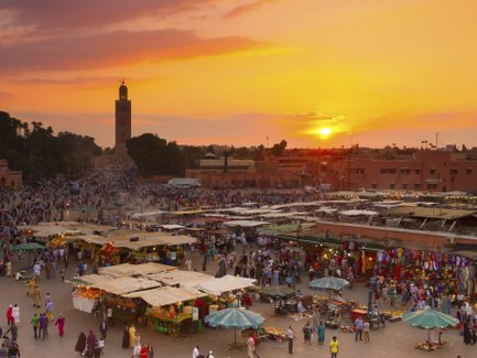 Djemaa el Fna Platz mit Menschen und Marktständen im Licht des Sonnenuntergangs in Marrakesch – Marokko Reise mit Kindern