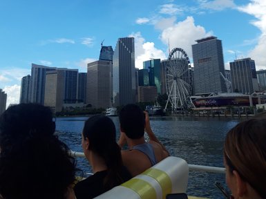 Die Skyline von Miami wird von einem Boot aus betrachtet, während Menschen am Rand des Bootes sitzen und die Aussicht genießen.