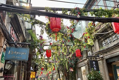 Eine belebte Straße im Künstlerviertel von Shanghai, geschmückt mit roten Laternen und üppigem Grün.