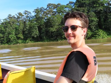 Teenager posiert lächelnd auf dem Boot während der Flusssafari auf dem Kinabatangan-Fluss – Malaysia & Borneo mit Kindern