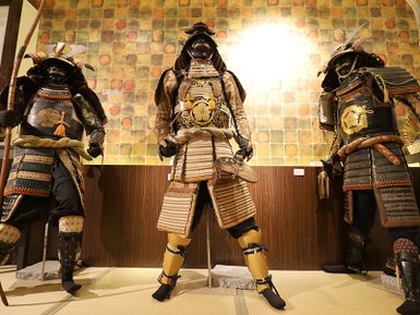 Drei beeindruckende Samurai-Rüstungen stehen in einem Museum, umgeben von einer stilvollen Wandgestaltung.