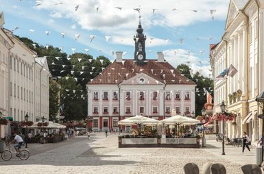 Eine belebte Straße in Tartu, mit einem historischen Gebäude im Hintergrund und bunten Wimpeln, die über die Straße hängen.