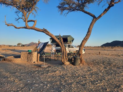 Ein Jeep mit Dachzelt steht neben einem aufgebauten Camp - Namibia mit Jugendlichen