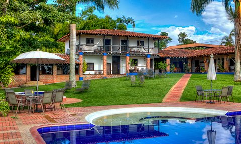 Ein einladender Außenbereich mit einem Pool, umgeben von üppigem Grün und einem charmanten, zweigeschossigen Gebäude.