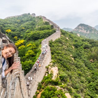 Teenager grüßt von der Großen Mauer mit weitem Blick auf die Landschaft Chinas – China Reise mit Kindern
