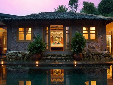 Ein traditionelles vietnamesisches Poolhaus mit einem ruhigen Wasserbecken und sanften Lichtern, umgeben von üppigem Grün.