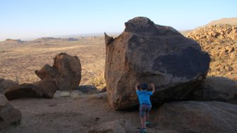 Ein Kind deutet an, einen großen Felsen zu verschieben - Namibia Urlaub mit Kindern