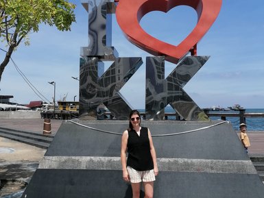 Frau steht vor dem berühmten Kota Kinabalu Schriftzug und genießt den Ausblick auf die Küste – Malaysia & Borneo mit Kindern