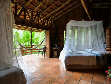 Die hübsche Lodge bietet zwei Betten mit Moskitonetzen, das warme Licht strahlt durch die Fenster und die Natur ist sichtbar.