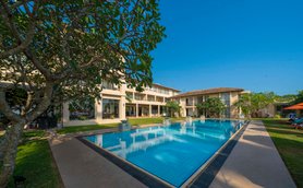 Ein klarer Pool spiegelt die Sonne wider, umgeben von modernen Gebäuden und üppigem Grün im Mirissa Mandara Resort.