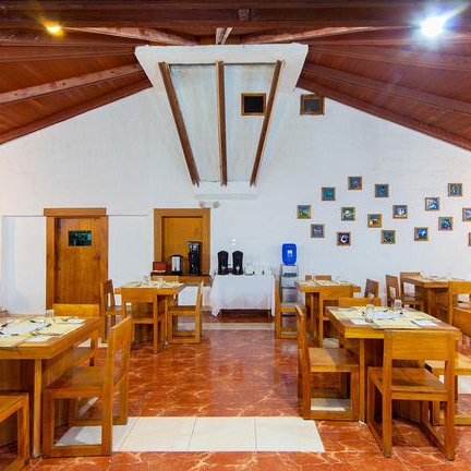 Ein einladender Restaurantbereich mit Holztischen und Stühlen, umgeben von warmen, rustikalen Wänden und einem hohen Dach.