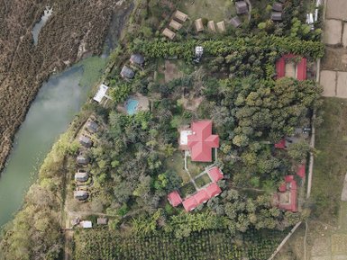 Eine Luftaufnahme eines malerischen Lodges mit roten Dächern, umgeben von üppigem Grün und einem ruhigen Gewässer.
