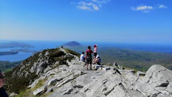 Eine Gruppe von Wanderern genießt die atemberaubende Aussicht auf die Küste und das grüne Land von Connemara.