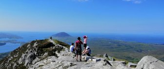 Eine Gruppe von Wanderern genießt die atemberaubende Aussicht auf die Küste und das grüne Land von Connemara.