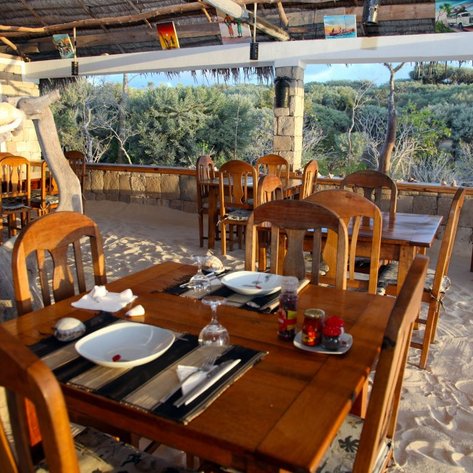 Ein einladendes Restaurant mit Holztischen und Stühlen, umgeben von einer natürlichen Landschaft und sanftem Licht.