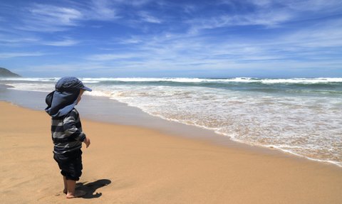 Kind steht an der Küste und blickt aufs Meer – Garden Route mit Kindern