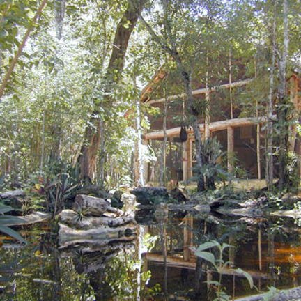 Ein malerisches Hotel umgeben von üppigem Grün und einem ruhigen Teich, der die Natur widerspiegelt.