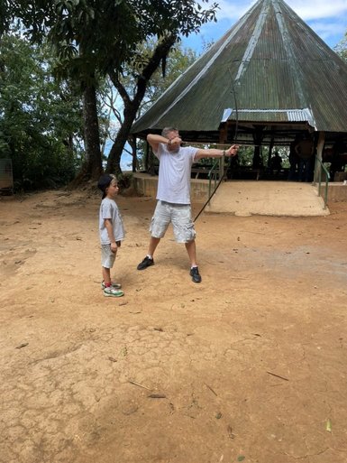 Vater zeigt Kind das Bogenschießen – Costa Rica Reise mit Kindern