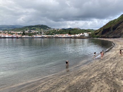An einem ruhigen Strand spielen Kinder im flachen Wasser, während die sanften Wellen sanft an den Sandstrand plätschern.
