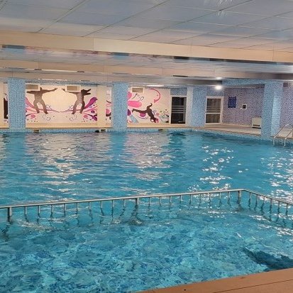 Ein Innenpool mit klarem Wasser, umgeben von bunten Wandmalereien und einem Holzdeck, bietet eine entspannende Atmosphäre.