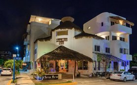 Das Matan K'aan Hotel präsentiert sich mit einem einladenden Eingangsbereich und einem strohgedeckten Dach in der Nacht.