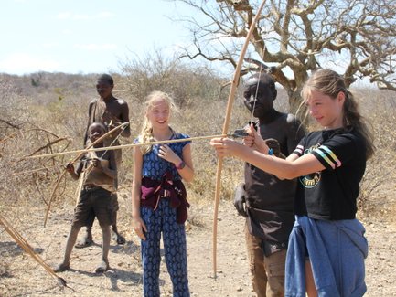 Jugendliche des Hadzabe-Stamms übt Bogenschießen – Tansania mit Kindern