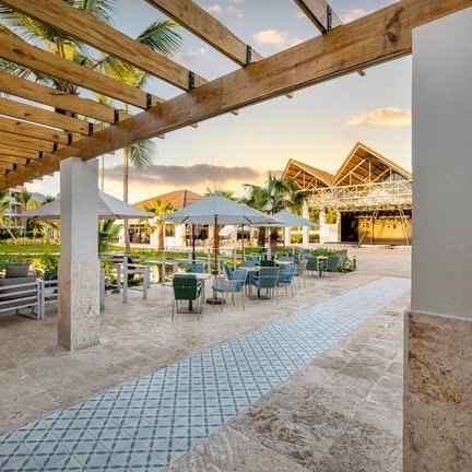 Ein einladender Außenbereich mit modernen Möbeln, umgeben von Palmen und einem klaren Himmel im Hintergrund.